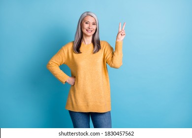 Hi Neighbor. Photo Of Cute Pretty Old Lady White Grey Hairdo Show V-sign Hand Hip Toothy Beaming Smile Meet Friend Greeting Wear Yellow Pullover Isolated Blue Pastel Color Background