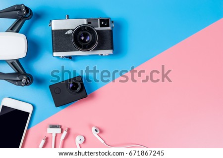 Hi tech travel gadget and accessories on blue and pink copy space, including drone camera mobile phone top view flay lay for Vacation Video footage filming tools. 