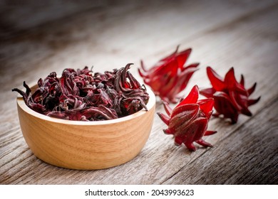 Hibiscus sabdariffa flower (Jamaica sorrel, Rozelle or Roselle ) in wooden bowl isolated on wood table background.