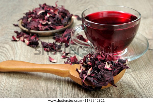 Hibiscus tea.\
Hibiscus tea in a wooden spoon on a background of a cup of fresh\
tea. Vitamin tea for cold and\
flu.