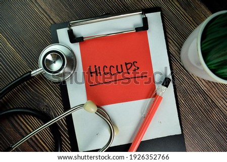 HICCUPS write on sticky notes isolated on Wooden Table.