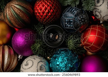 Hidden camera lens looking through Shiny colorful christmas balls with fir branches. Photography background. Christmas background.