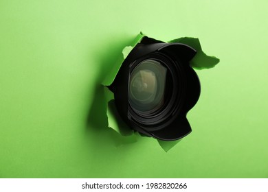 Hidden Camera Lens Through Torn Hole In Green Paper