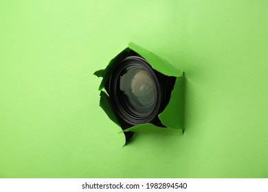 Hidden Camera Lens Through Torn Hole In Green Paper