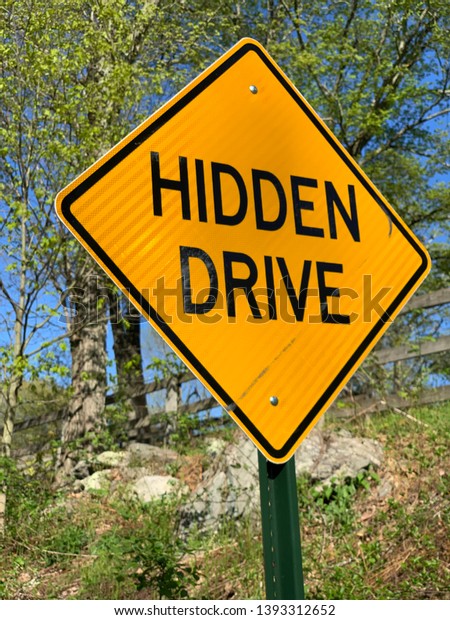 Hidden Drive Sign for a driveway that is\
around corner.  Drive slow be cautious\
sign.