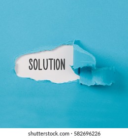 Hidden solution revelaed on torn blue paper secret behind ripped opening. - Shutterstock ID 582696226