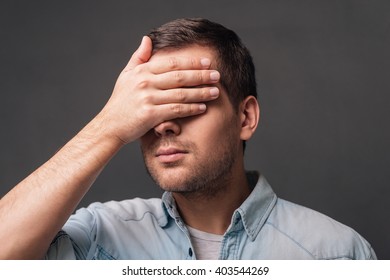 Hide And Seek! Young Handsome Man Covering His Eyes With His Hand While Standing Against Grey Background