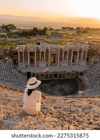 Hierapolis ancient city Pamukkale Turkey, a young woman with a hat watching the sunset by the ruins Unesco. Asian women watching sunset at the old Amphitheater in Turkey 