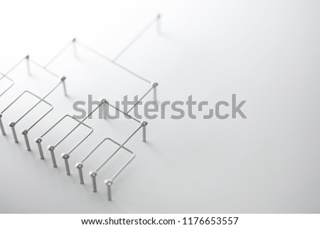 Hierarchy, command chain, company / organization structure or layer concept image. Top down structure made from chrome wires and chrome nails on white. Shallow depth of field.