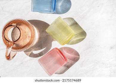 High Above View Of Colored Jug Of Water And Transparent Glasses On Table. Kitchen Tableware Flat Lay. Minimalism Style. Home Comfort Concept