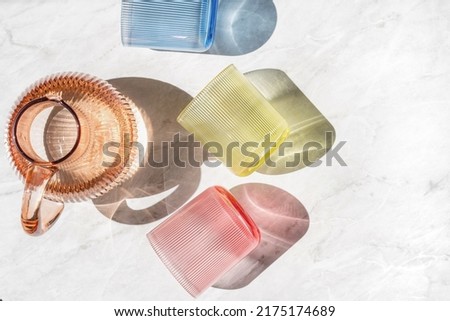 High above view of colored jug of water and transparent glasses on table. Kitchen tableware flat lay. Minimalism style. Home comfort concept