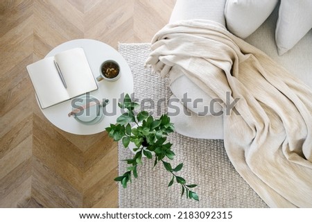 High above view of open book, plant, tea and couch in living room interior design. Home comfort concept. Relax idea. Flat lay. House details