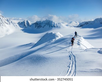High altitude view of two skiers walking on a mountain ridge in the Lyngen Alps, Norway