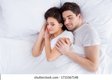 High angle above top view photo charming lady husband guy couple lying comfortable sheets bed white blanket hugging joyful hold touch arms eyes closed wear pajama room indoors