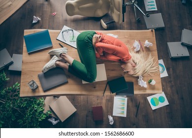 High angle above view photo of corporate messy atmosphere unorganized blond business lady lying table suffering period pms holding hurt belly wear casual outfit indoors