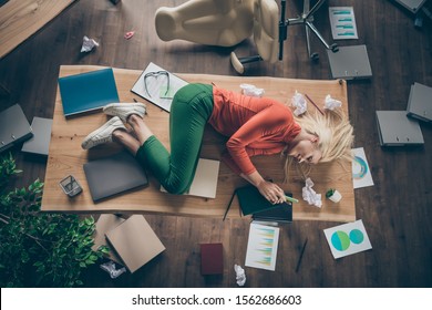 High angle above view photo of corporate messy atmosphere unorganized blond business lady lying table don't mind cluttered office texting telephone wear casual outfit indoors