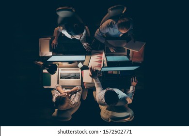 High angle above view photo of hard-working four busy business men women working overtime looking computer screen talking about startup lamp light dark office indoors - Shutterstock ID 1572502771