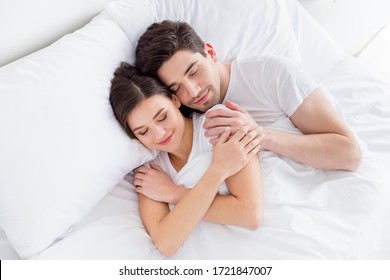High angle above view photo charming cute lady husband guy couple lying comfortable sheets bed white blanket hugging joyful hold touch hands eyes closed wear pajama room indoors