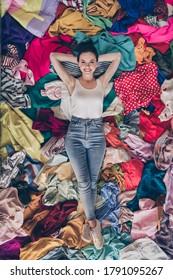 High angle above view vertical photo of pretty lady stay home quarantine general spring cleaning household lying many clothes heap stack floor shopaholic shopper addiction obsession indoors