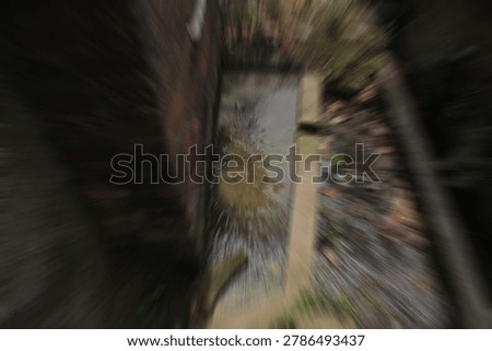 High angle abstract motion blur of dirty water puddle inside a narrow brick drain tunnel
