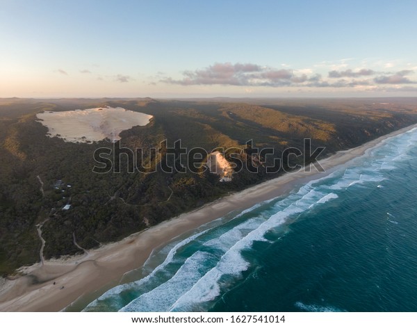 High angle aerial drone view of famous\
Seventy Five Mile Beach near Dundubara Creek on Fraser Island,\
Queensland, Australia, shortly before sunset. \