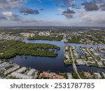 A high angle, aerial view of Boynton Beach Florida on a sunny morning with blue skies and clouds, showing the Atlantic Ocean, the Inlet and luxury homes.