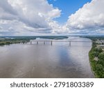 High angle aerial view of the Hernando de Soto Bridge spanning the wide Mississippi River with a boat leaving a wake in the water.