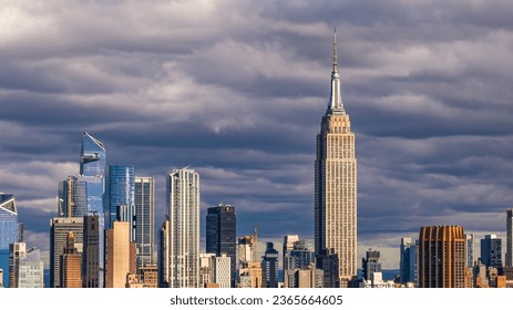 A high angle, aerial view of Manhattan from over the East River in New York on a sunny day with clear blue skies and white clouds.