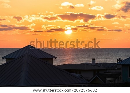 High angle aerial view on colorful yellow sunset ocean landscape horizon of Gulf of Mexico in Seaside, Florida and buildings houses cityscape