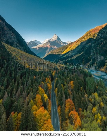 High angle aerial view of river and road running through forest and mountainous landscape