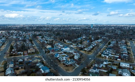 A High Angle Aerial View Of A Suburban Neighborhood On Long Island, NY, Taken With A Drone On A Cloudy Day With Blue Skies.