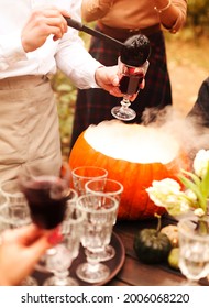 High Angle Of Anonymous People Filling Glass Goblets With Punch Near Pumpkin Bowl During Halloween Celebration