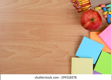 High Angle Back To School Still Life On Top Of A Wood Teachers Desk. An Apple, Note Pads, Pencils And Erasers With Copy Space.