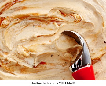 High Angle Close Up of Red Handled Ice Cream Scoop Scooping a Serving of Caramel Butterscotch Ripple Ice Cream