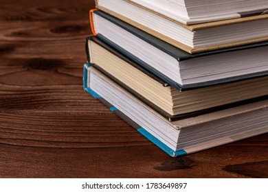 High angle close up of stack of books on wooden table. Books in the library on the table. Literature about business. Novels and tales, adventures, stories. The background for design