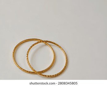 High angle close up of two round golden bracelets on left side with large empty copy space.