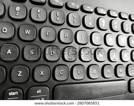 High angle close up view of a modern black computer keyboard with round QWERTY keys.