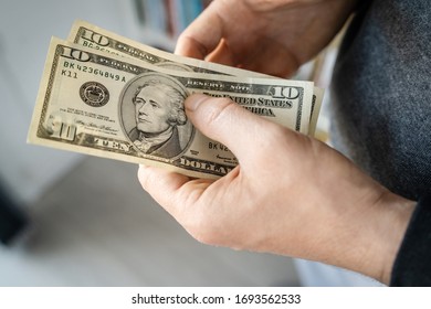 High angle close up view of unknown caucasian man midsection holding american dollars USD banknotes money in hand at home in day