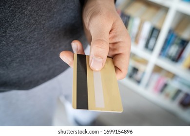 High angle close up view of unknown caucasian man midsection holding plastic credit or debit or membership card in hand at home in day
