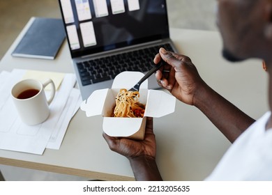 High Angle Close Up Of Young Black Man Eating Takeout Noodles At Workplace During Lunch Break