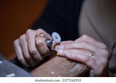 High angle closeup of crop unrecognizable female goldsmith using special tool with rotating disc while polishing jewellery in workshop - Powered by Shutterstock