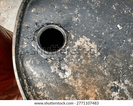 High angle close-up of a rusty and weathered metal oil drum lid with an open bung hole, showing industrial wear, corrosion, and oil residue.