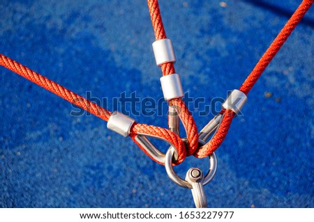 A high angle closeup shot of three red ropes attached to a metal holder with a blue background
