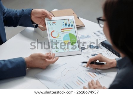 High angle closeup of two unrecognizable colleagues discussing data statistics on tablet screen during meeting in office copy space