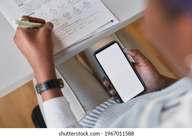 High Angle Closeup Of Unrecognizable African-American Student Holding Smartphone With Blank Screen While Taking Math Test In School, Cheating At Exam Concept, Copy Space
