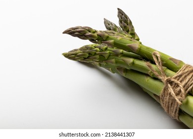 High angle close-up view of asparagus tied with string by copy space on white background. unaltered, food, healthy eating and organic concept.