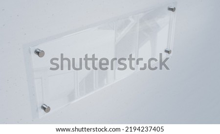 High angle close-up view of blank glass nameplate mounted on white wall, copy space. Unaltered, shape, no people, communication, modern, rectangle.
