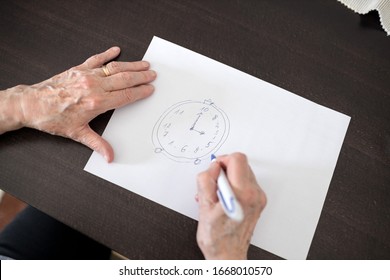 High Angle Close-up View Of A Senior Caucasian Woman's Hands Drawing Alzheimer's Disease Cognitive Functions Clock Test With Positive Results Suggesting Illness