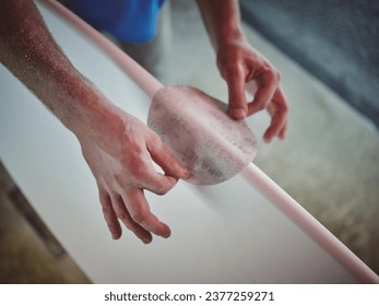 High angle of crop anonymous handyman with tattoos shaping and sanding wooden surfboard in workshop - Powered by Shutterstock