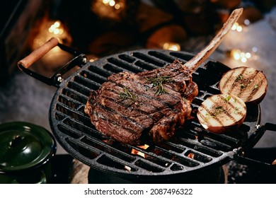 High angle of delicious hot Tomahawk steak and halves of onion preparing on grill rack in winter night - Shutterstock ID 2087496322